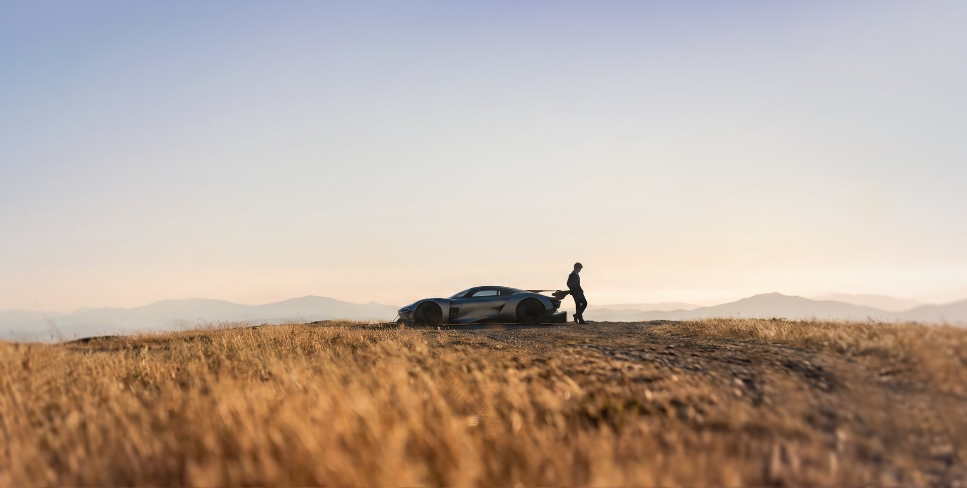 Michael To standing beside a concept car in a golden field at dawn